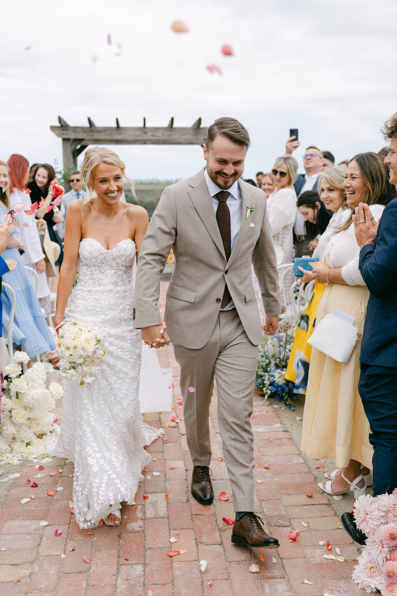 Bride and groom walking down the aisle after their wedding ceremony with petals being tossed at Warrawong Estate